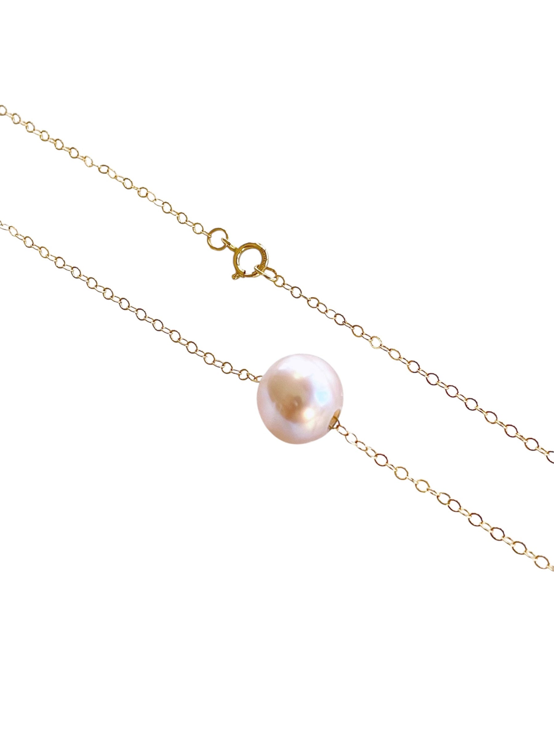 Gold chain necklace with a single pearl on a white background