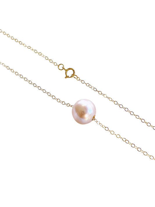 Gold chain necklace with a single pearl on a white background